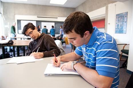 两个学生坐在桌子旁记笔记.