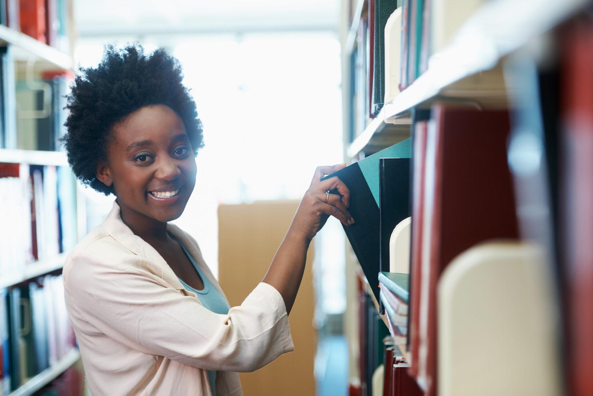 一位年轻女子在图书馆里挑选书