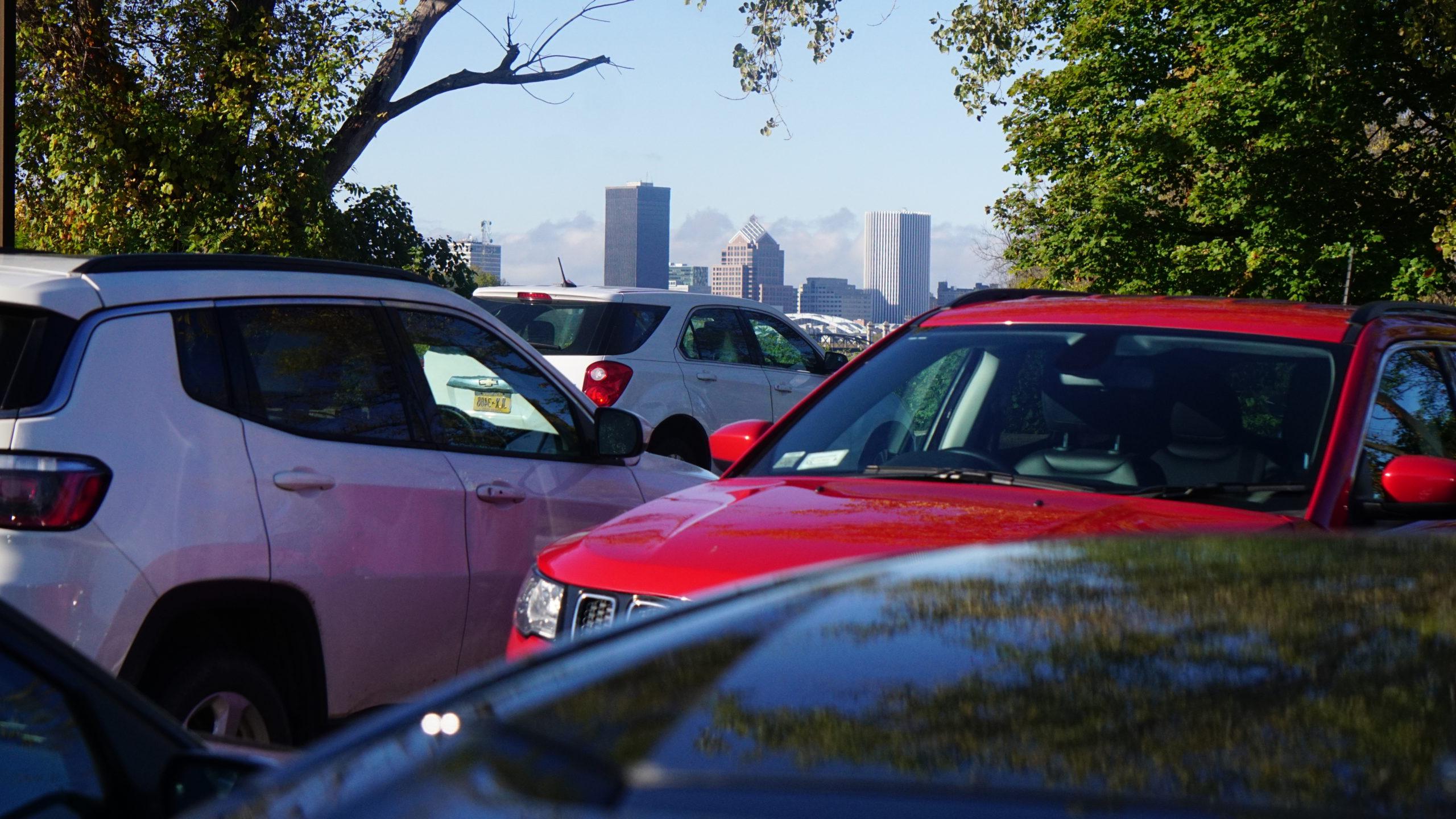 红色和白色的车辆停在停车场，背景是纽约十大赌博正规老平台市的天际线